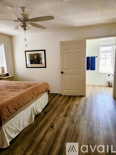 A bedroom with a bed, a ceiling fan, and a door leading to another room.
