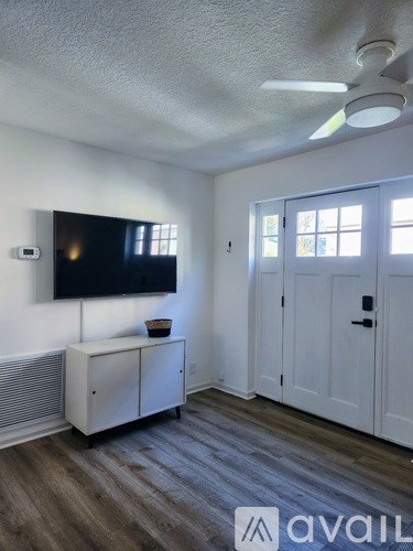A room with a television, a cabinet, and a ceiling fan.