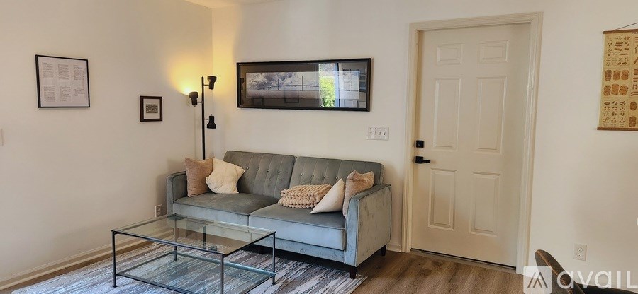 A living room with a grey couch and a glass coffee table.