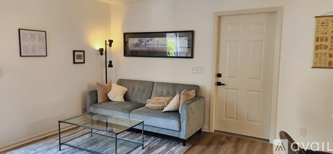 A living room with a grey couch and a glass coffee table.