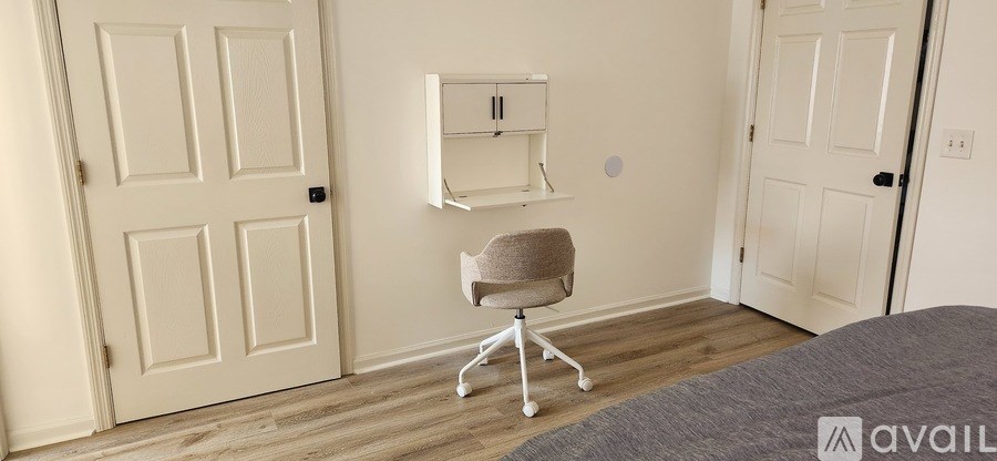 A white chair is in a room with a mirror and a bed.