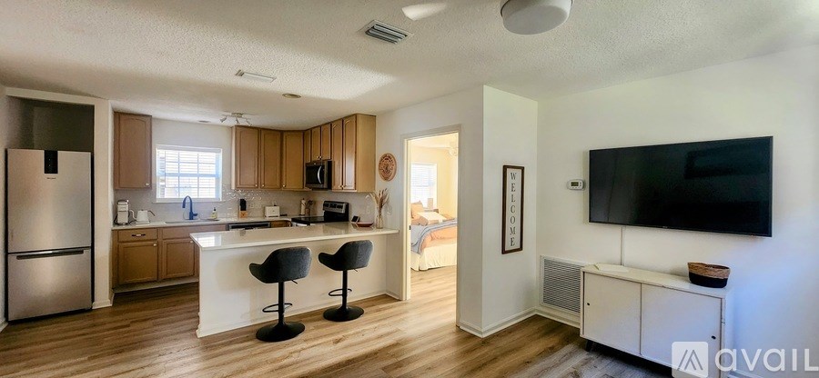 A kitchen with a refrigerator, a counter, and a television.