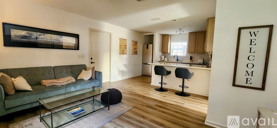 A living room with a green couch and a glass coffee table.