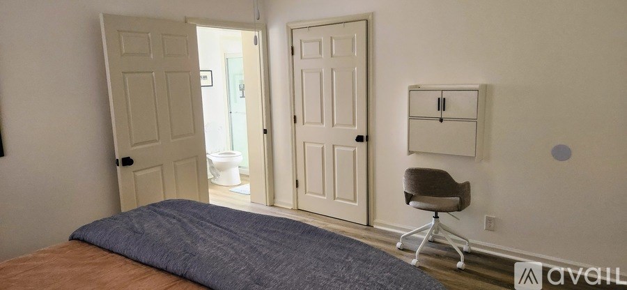 A bedroom with a bed, chair, and cabinet.