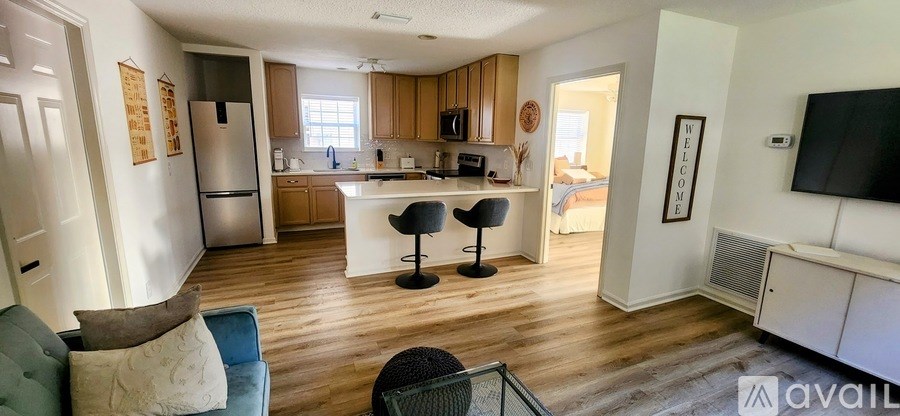 A kitchen with a refrigerator, a counter, and a bar stool.