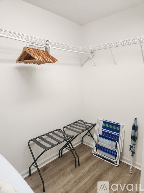A room with a clothes rack, two chairs, and a small table.