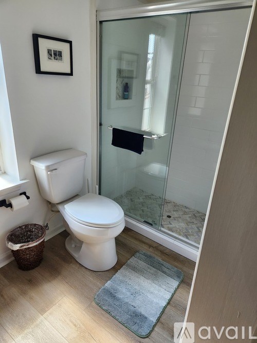 A white toilet sits in a bathroom next to a glass shower door.