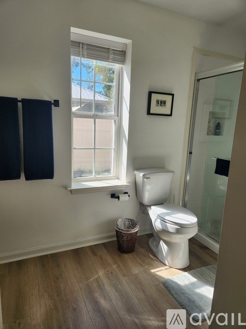 A white toilet sits in a bathroom next to a window.