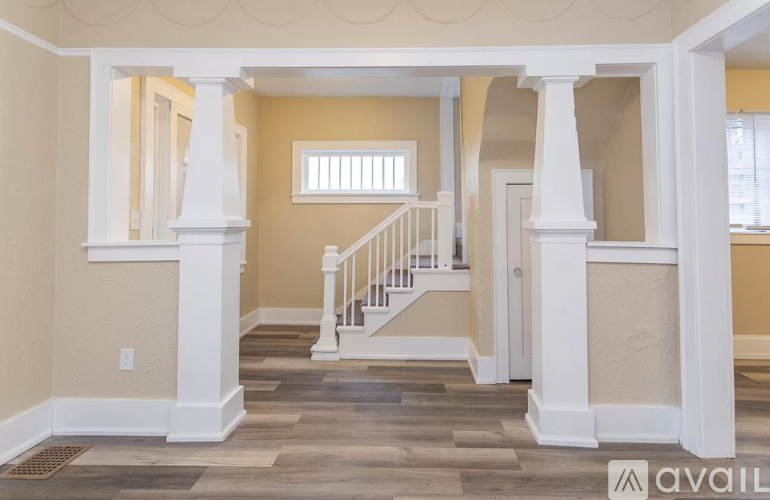 A spacious room with a staircase and pillars.