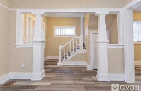 A spacious room with a staircase and pillars.