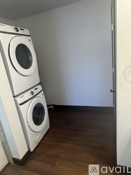 A white washing machine and dryer in a room with wooden floors.
