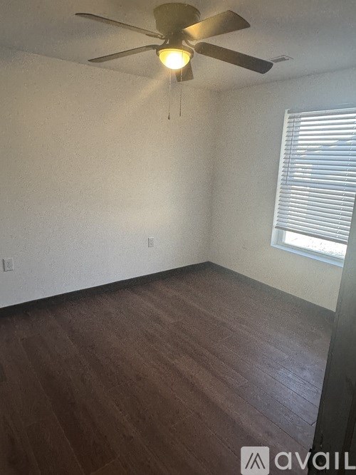 A room with a ceiling fan and wooden flooring.