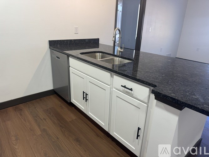 A kitchen with white cabinets and a black countertop.
