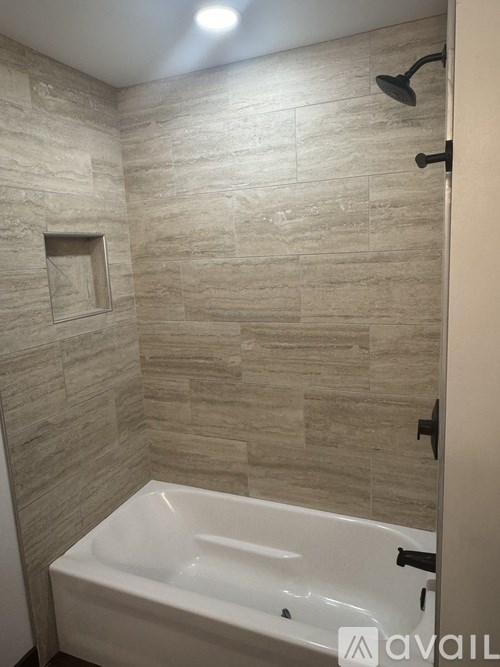 A bathroom with a white tub and a shower head.