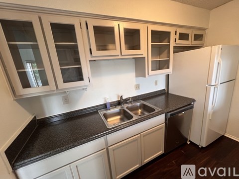 A kitchen with white cabinets and a black countertop.