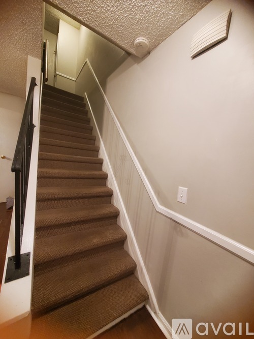 A staircase with a carpeted runner and a black handrail.