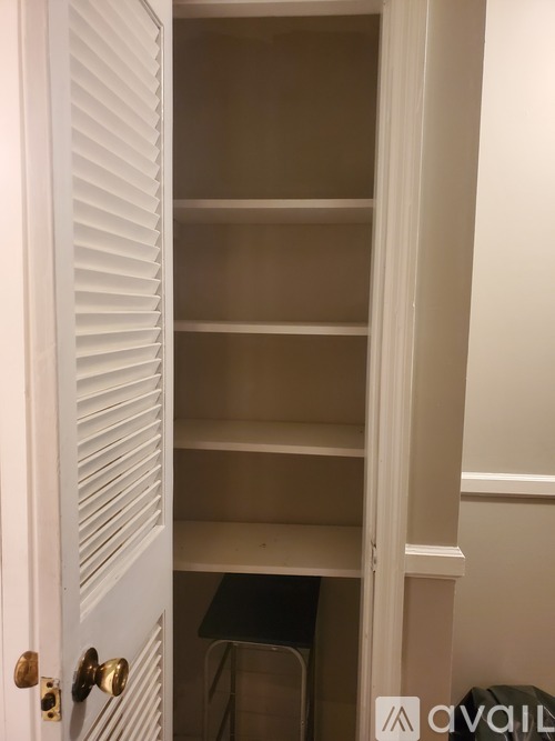 A white door with a gold handle is open to a dark room.