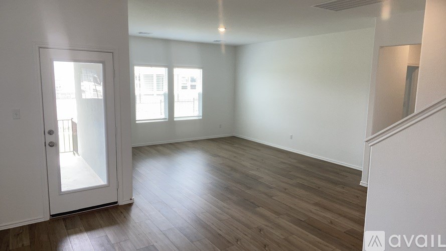 A room with wooden flooring and a door leading to a balcony.