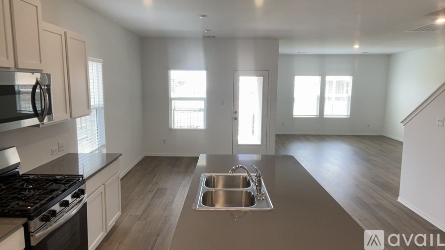 A kitchen with a stove, sink, and cabinets.