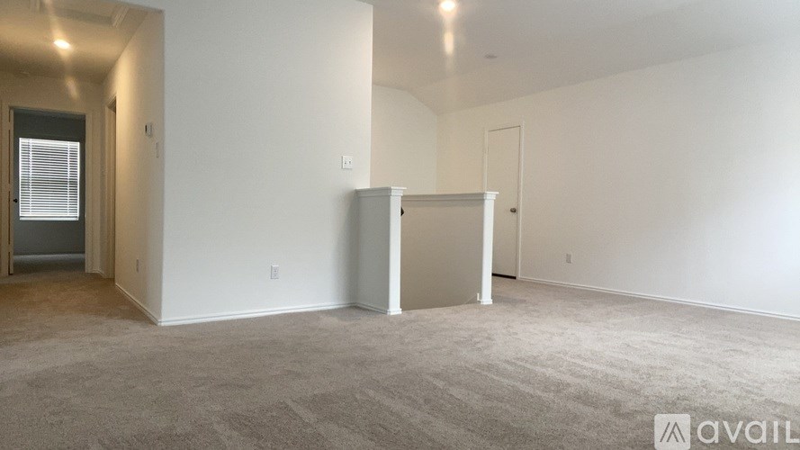 A spacious room with a carpeted floor and white walls, with a door on the right side.