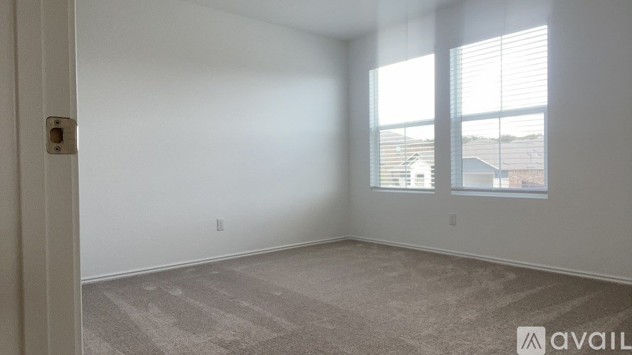 A room with a carpeted floor and a window with blinds.