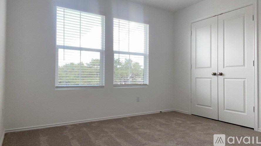 A room with a large window and a white door is available for rent.