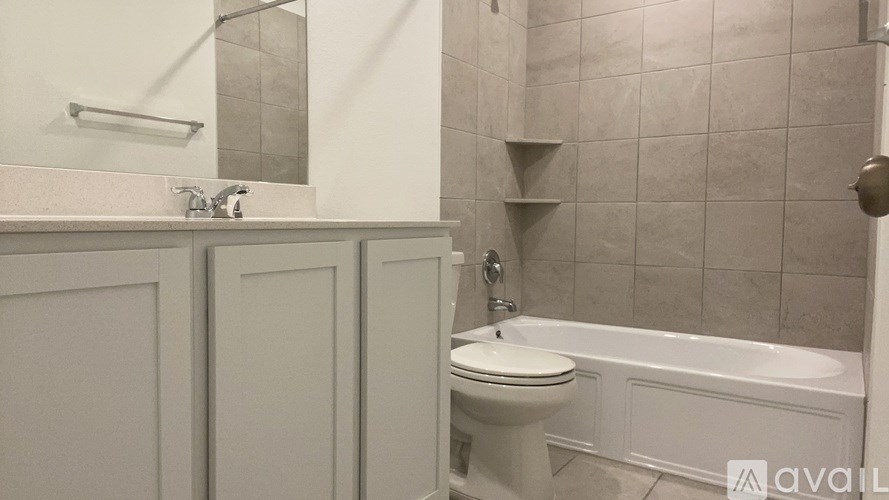 A white toilet sits next to a white bathtub in a bathroom.