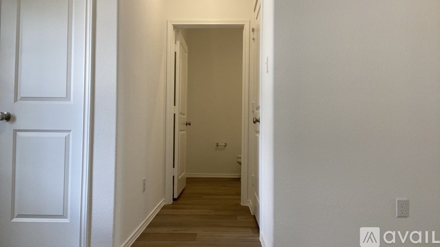 A hallway with a door on the left and a wall on the right.
