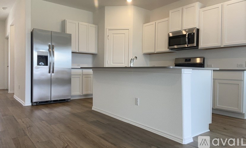 A kitchen with a refrigerator, microwave, and cabinets.