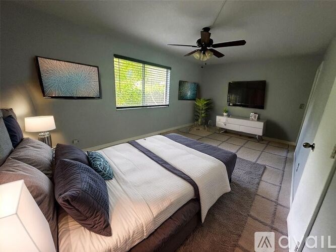 A bedroom with a bed, a ceiling fan, and a window.