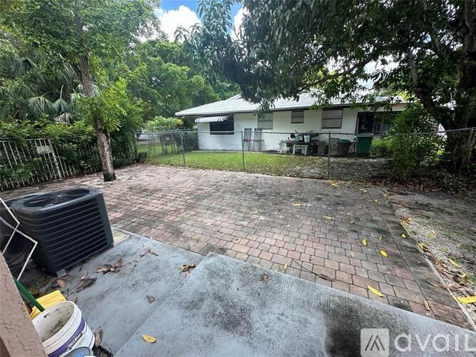 A backyard with a brick patio and a tree.