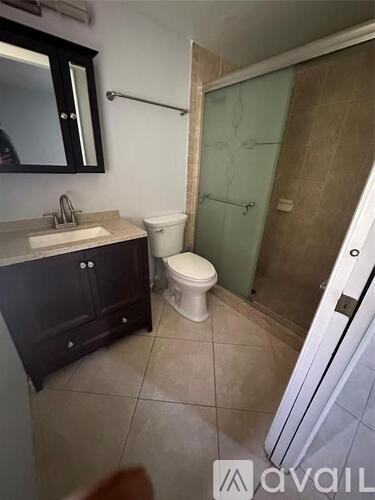 A bathroom with a toilet, sink, and shower.