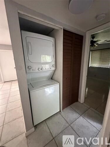 A white refrigerator is in a kitchen with a white tiled floor.
