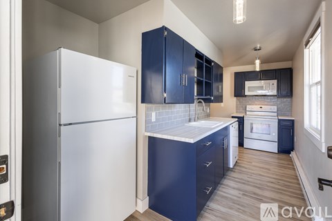 A kitchen with a white refrigerator and blue cabinets.