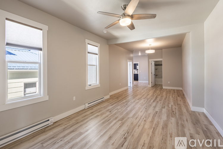 A spacious room with a ceiling fan and wooden flooring.