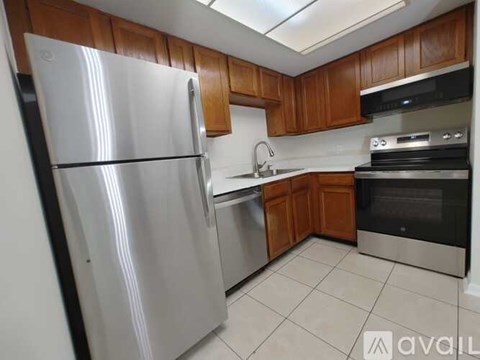 A kitchen with a stainless steel refrigerator and wooden cabinets.