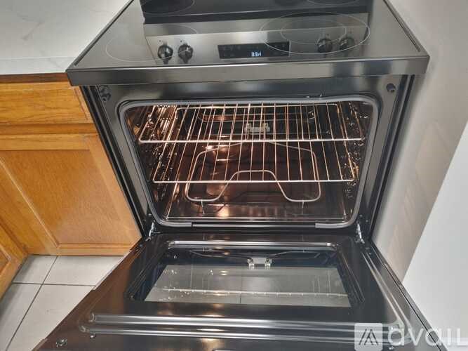 A modern stainless steel oven with the door open, revealing the interior racks.