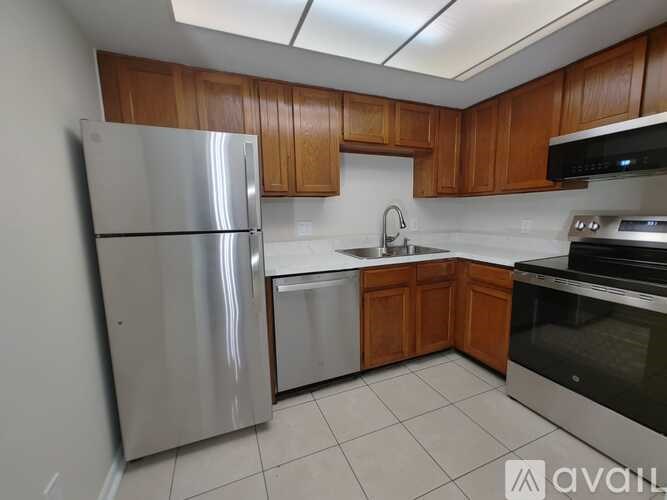A kitchen with wooden cabinets and a stainless steel refrigerator.