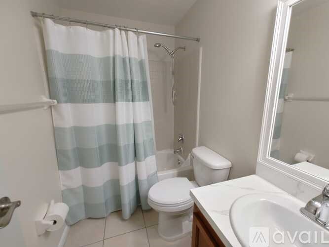 A bathroom with a toilet, sink, and shower curtain.