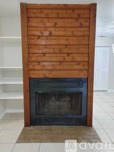 A wood fireplace with a black grate in the middle.
