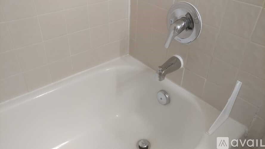 A white bathtub with a silver faucet and shower head.