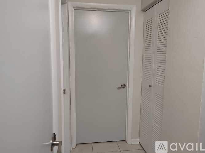 A white door with a silver handle is in a room with white walls.
