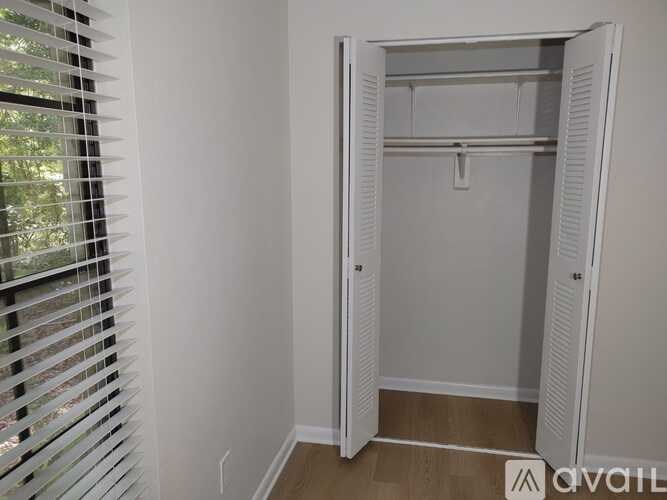 A white closet with a shelf and a hanger is open.
