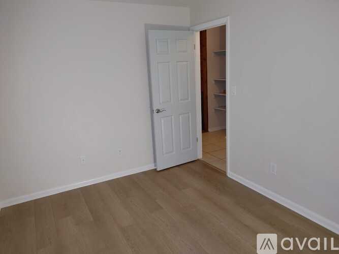 A room with a white door and wooden flooring.