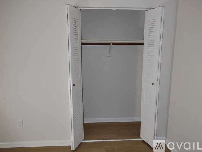 A white closet with a mirror and a hanger.