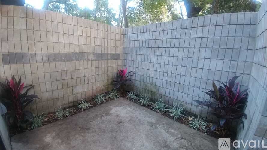 A patio area with a concrete floor and a wall made of square tiles.