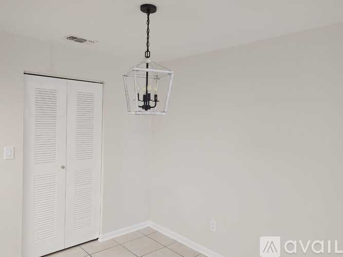 A room with a white door and a hanging light fixture.
