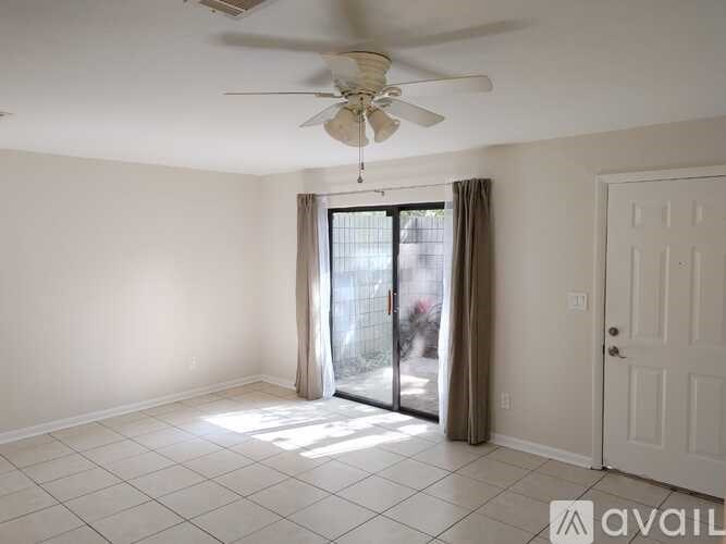 A room with a ceiling fan and sliding glass doors.