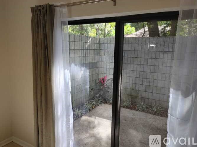 A room with a window that has a view of a fence and plants.