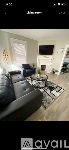 A living room with a black leather couch and a fireplace.